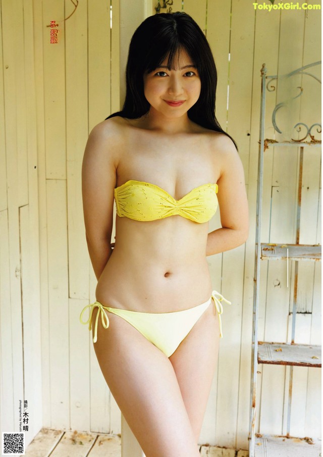 A woman in a yellow bikini posing for a picture.