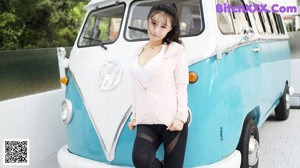 A woman in a white bra top and black pants posing for a picture.
