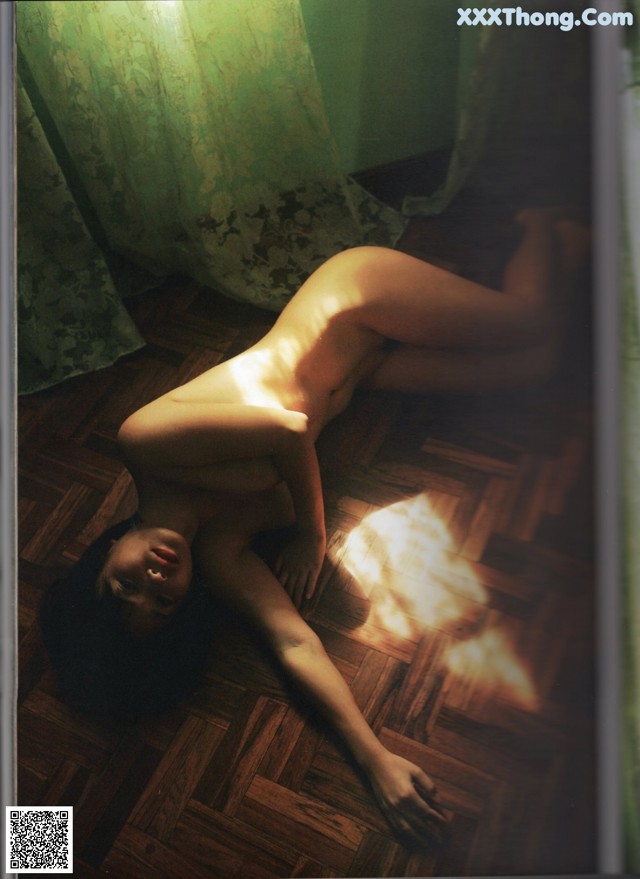 A naked woman laying on the floor in a room.