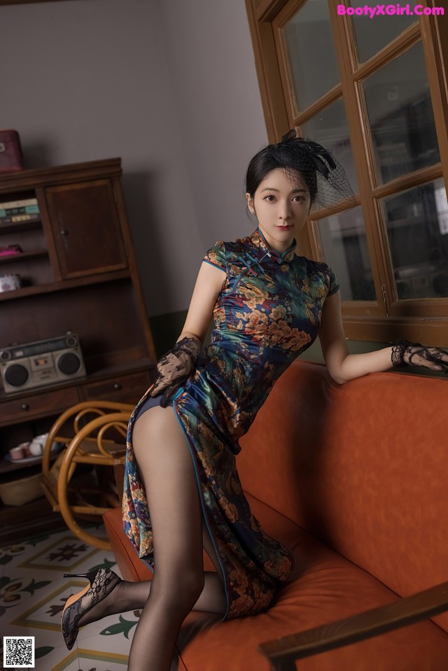 A woman in a dress sitting on a couch.