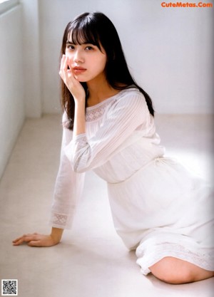A woman in a white dress is posing for a picture.