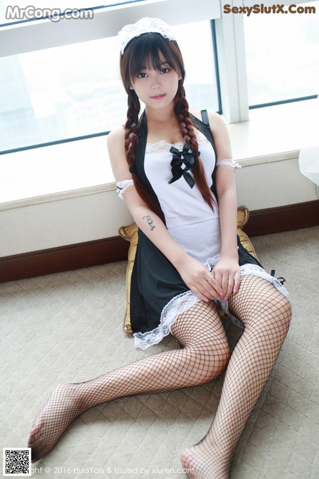 A woman in a maid outfit sitting on the floor.