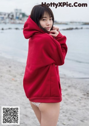 A woman in a bikini and a red hoodie posing for a magazine.