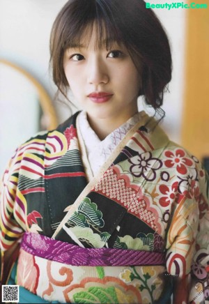 A woman in a kimono sitting on a chair.