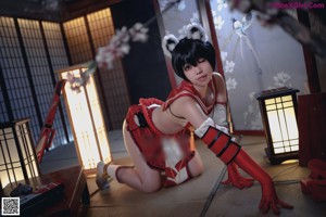 A woman in a red and white outfit sitting on the floor.