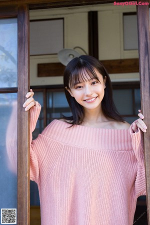 A woman in a pink sweater holding a bottle of water.