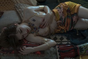 A woman in a white dress sitting on a bed.