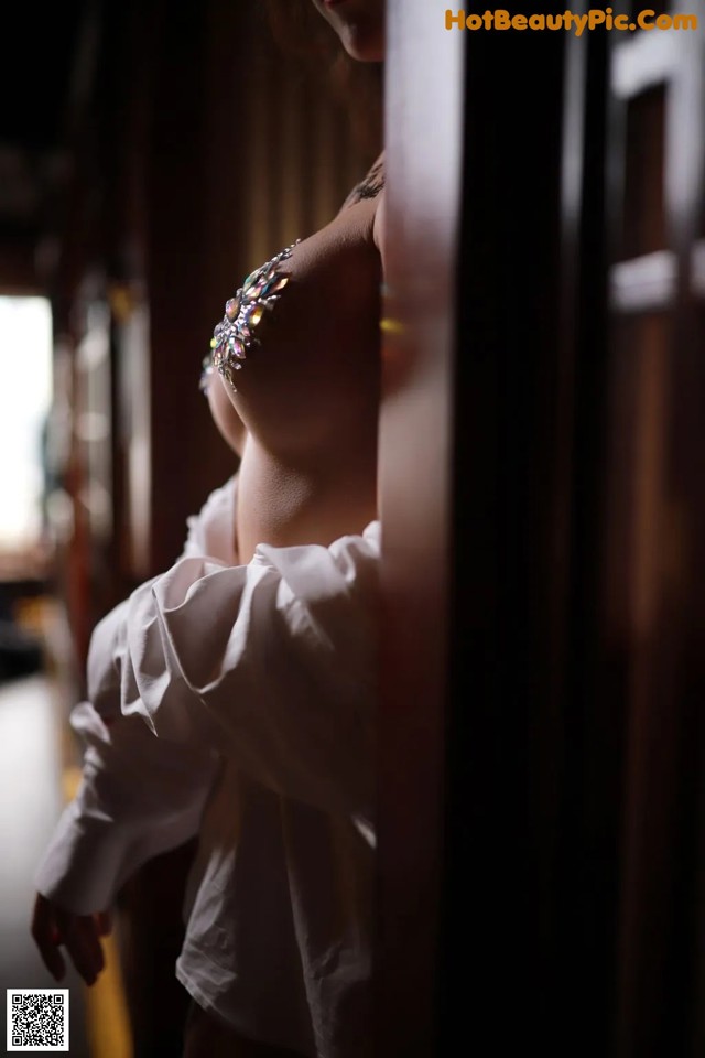 A woman in a white shirt leaning against a wall.