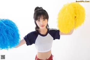 A woman in a white top and red shorts holding a red balloon.