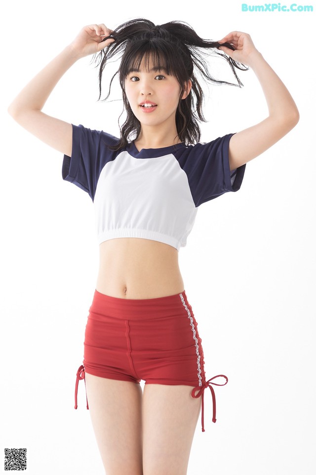 A woman in a white top and red shorts posing for a picture.