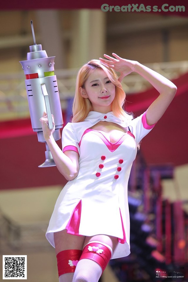 A woman in a white and pink outfit holding a gun.