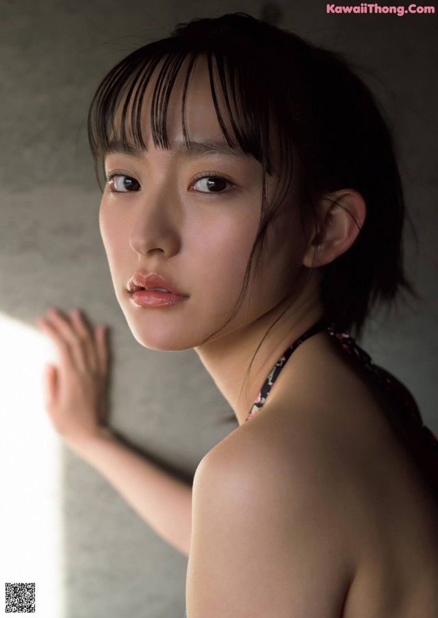 A woman in a blue dress leaning against a wall.