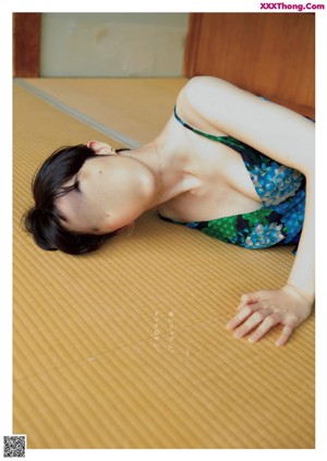 A woman in a blue bikini sitting on a wooden floor.