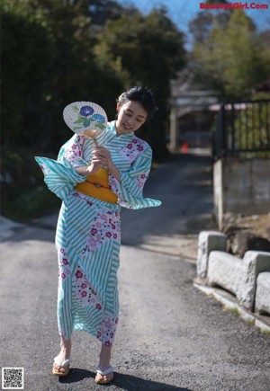 A woman in a kimono sitting on the floor next to a window.