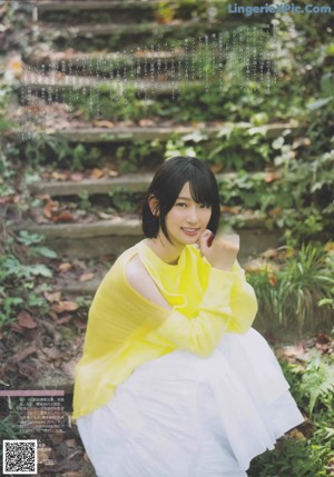 A woman in a yellow dress holding a flower in her hand.