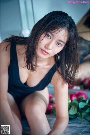 A woman in a black bathing suit holding a bunch of pink roses.