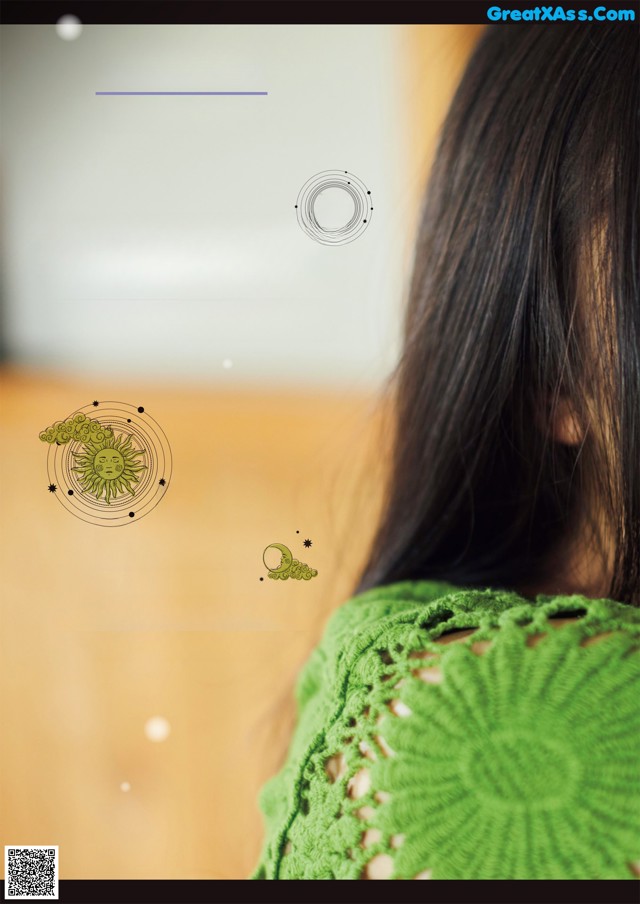 A woman with long black hair wearing a green sweater.