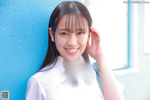 A young woman in a school uniform leaning against a blue door.