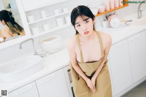 A woman standing in a kitchen next to a counter.