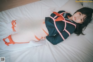 A woman in an orange bikini laying on a bed.