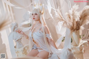 A woman in a white lingerie sitting on a chair.