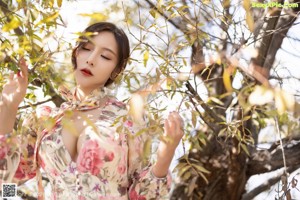 A woman in a white bra and floral kimono posing for a picture.