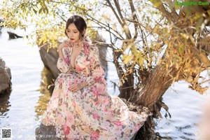 A woman leaning against a tree in a park.