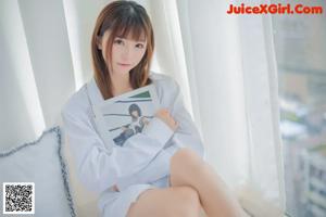 A woman in a white shirt sitting on a bed.
