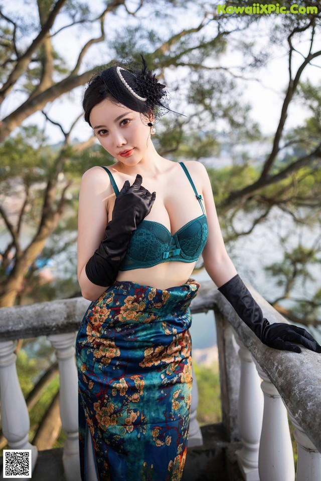 A woman in a green bra top and black gloves posing on a balcony.