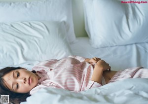 A woman laying in bed with her hands on her stomach.