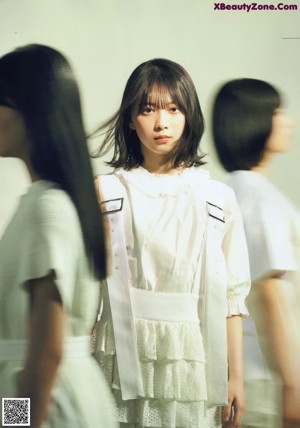 A woman standing in front of a wall of white circles.