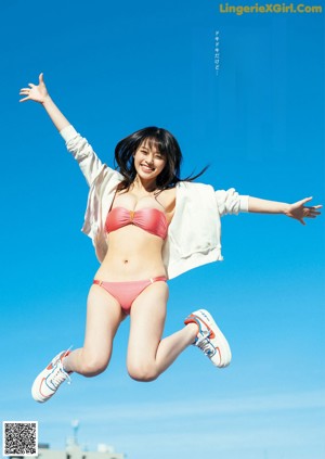 A woman in a blue bikini holding a pink flamingo.