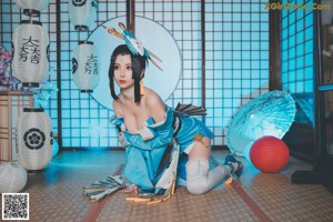 A woman in a blue and white outfit sitting on the floor.