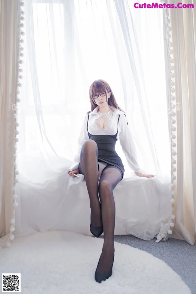 A woman sitting on a white couch wearing black stockings.