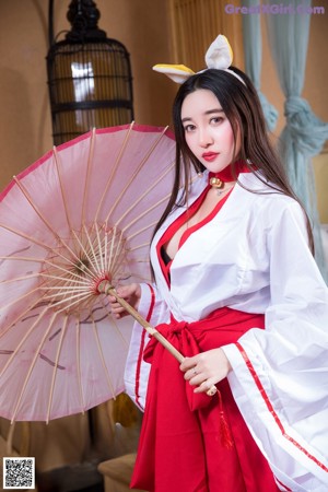 A woman in a red and white dress holding a pink umbrella.