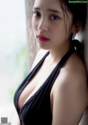 A woman in a black bathing suit sitting on a window sill.