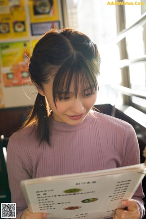 A woman in a yellow and white striped top and gray shorts.