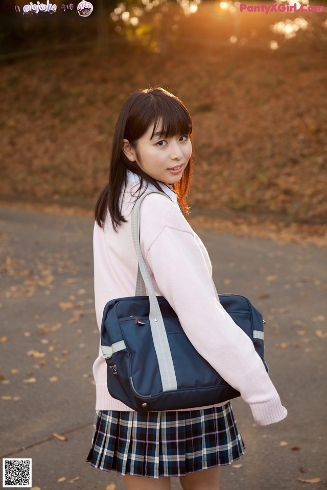 A young woman in a school uniform carrying a blue bag.