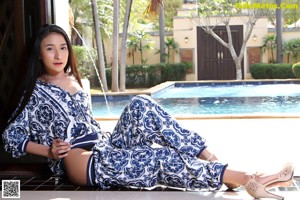 A woman in a bikini sitting by a swimming pool.