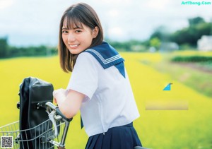 A woman in a school uniform standing in front of a field.