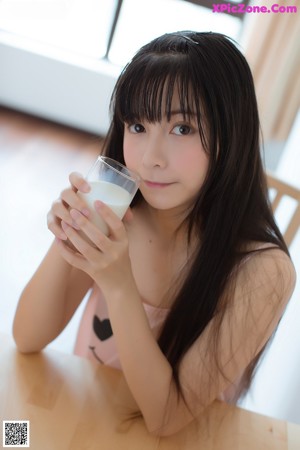 A woman in a pink dress holding a glass of milk.