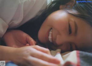 A young woman in a blue sweater smiles at the camera.