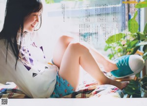 A woman laying on top of a bed next to a window.