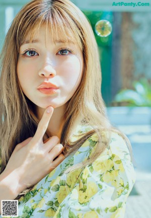 A woman with long brown hair is looking at the camera.