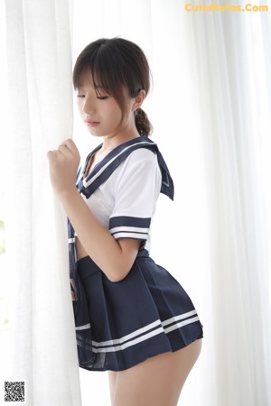 A woman in a sailor outfit sitting on the floor.