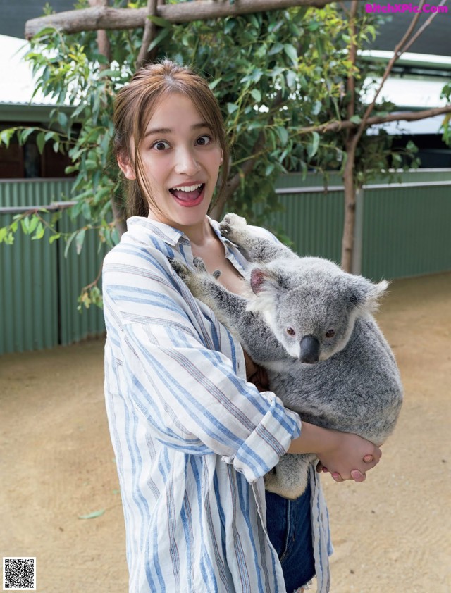 A woman holding a koala in her arms.