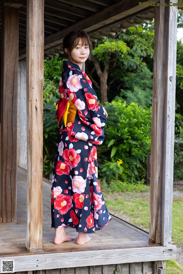 A woman in a kimono standing on a porch.