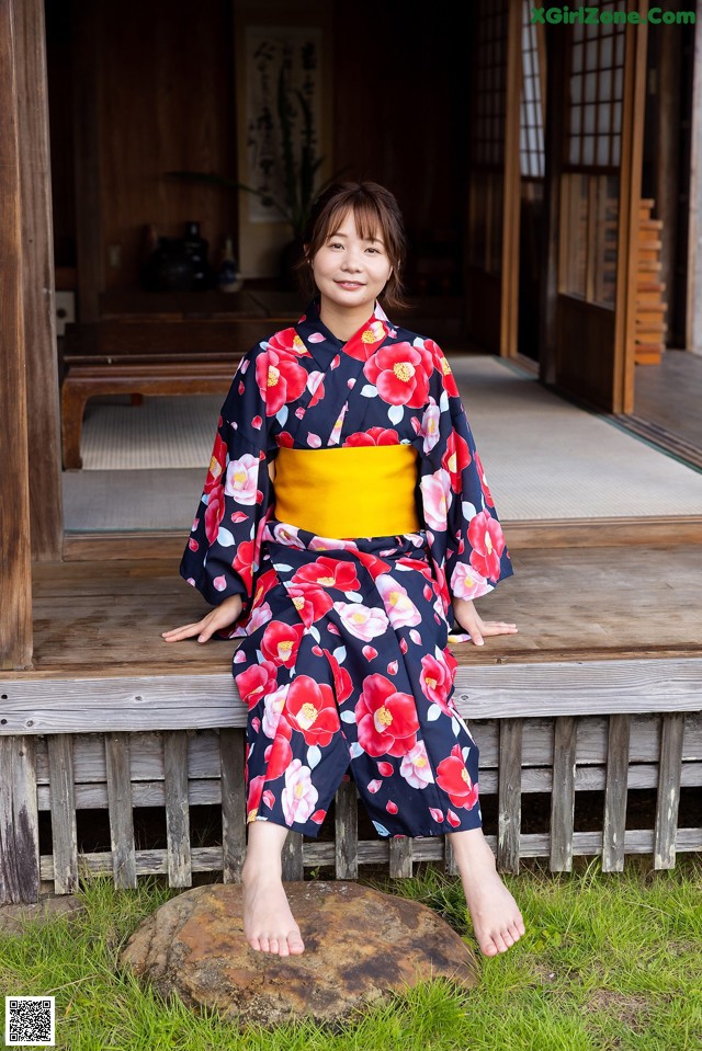 A woman in a kimono sitting on a wooden bench.