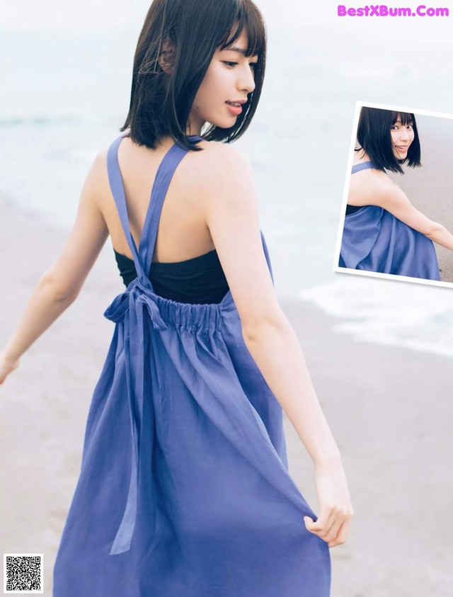 A woman in a blue dress walking on the beach.