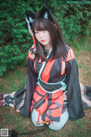 A woman in a black and red kimono sitting on the ground.